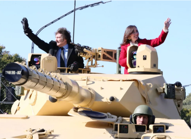  Milei y la vicepresidenta Victoria Villarruel posando juntos y sonrientes, mientras se encontraban subidos a un tanque militar.