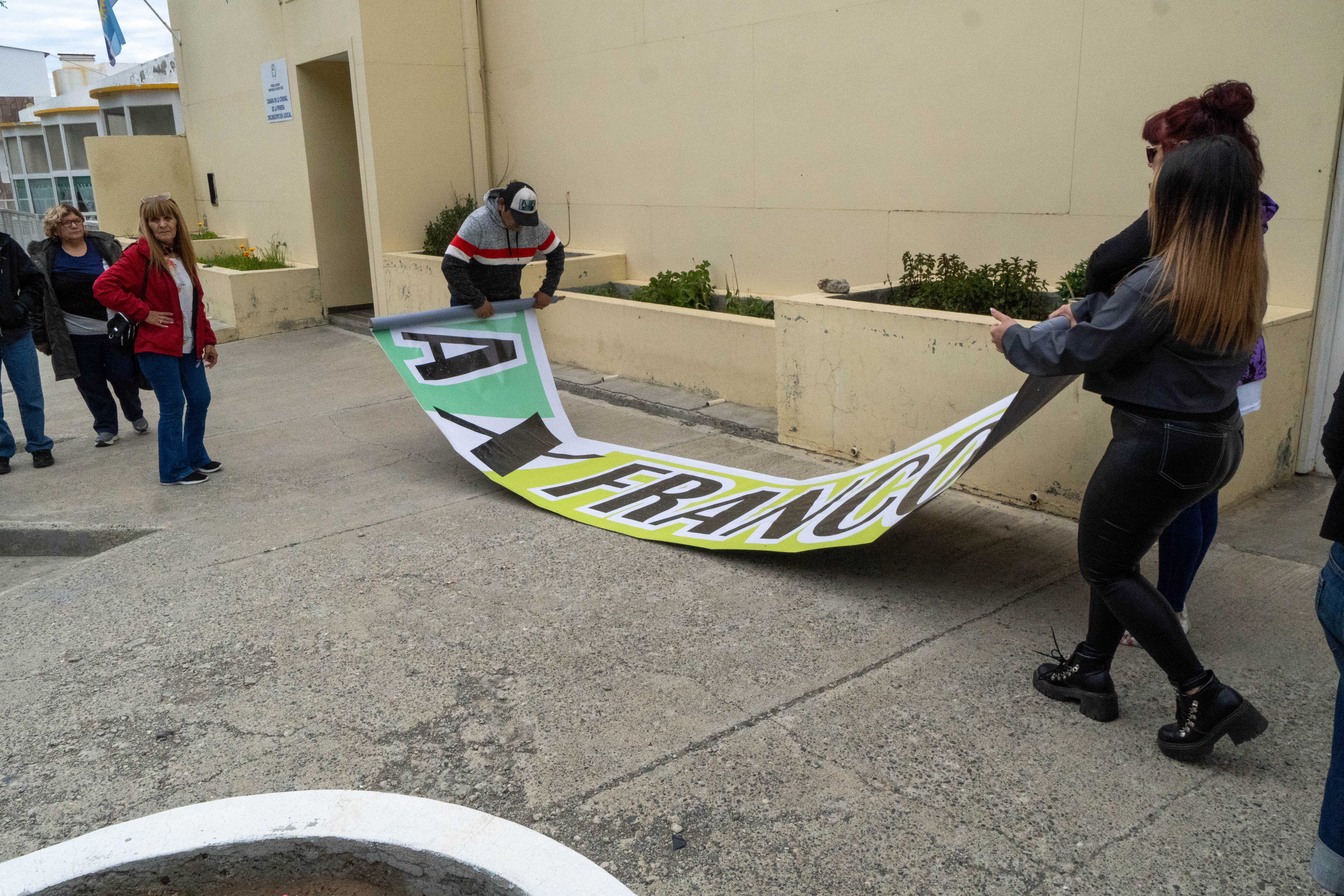  Los allegados a Franco enrollando la bandera con la que pedían justicia. FOTO: LEANDRO FRANCO/ LA OPINIÓN AUSTRAL