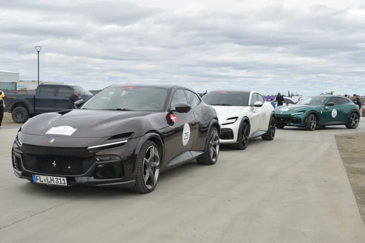  Una Ferrari encabeza la caravana al ingresar a la estación de servicio frente a la gente que observa desde la vereda. FOTO: JUAN PALACIOS / LA OPINIÓN AUSTRAL.