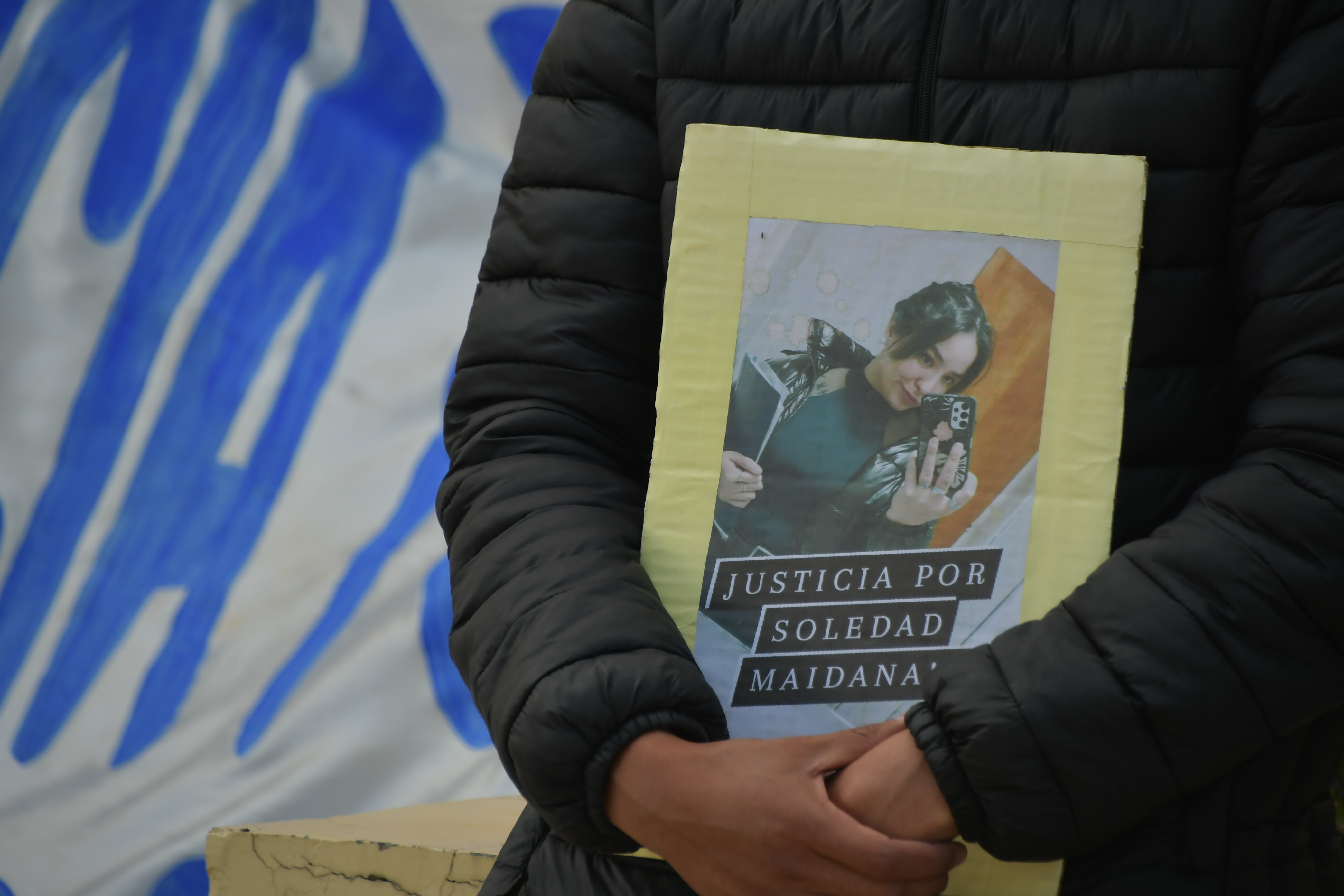  Una familiar de Soledad carga un cartel con su nombre. Atrás, la emblemática bandera que se muestra en el izamiento. JUAN PALACIOS/LA OPINIÓN AUSTRAL